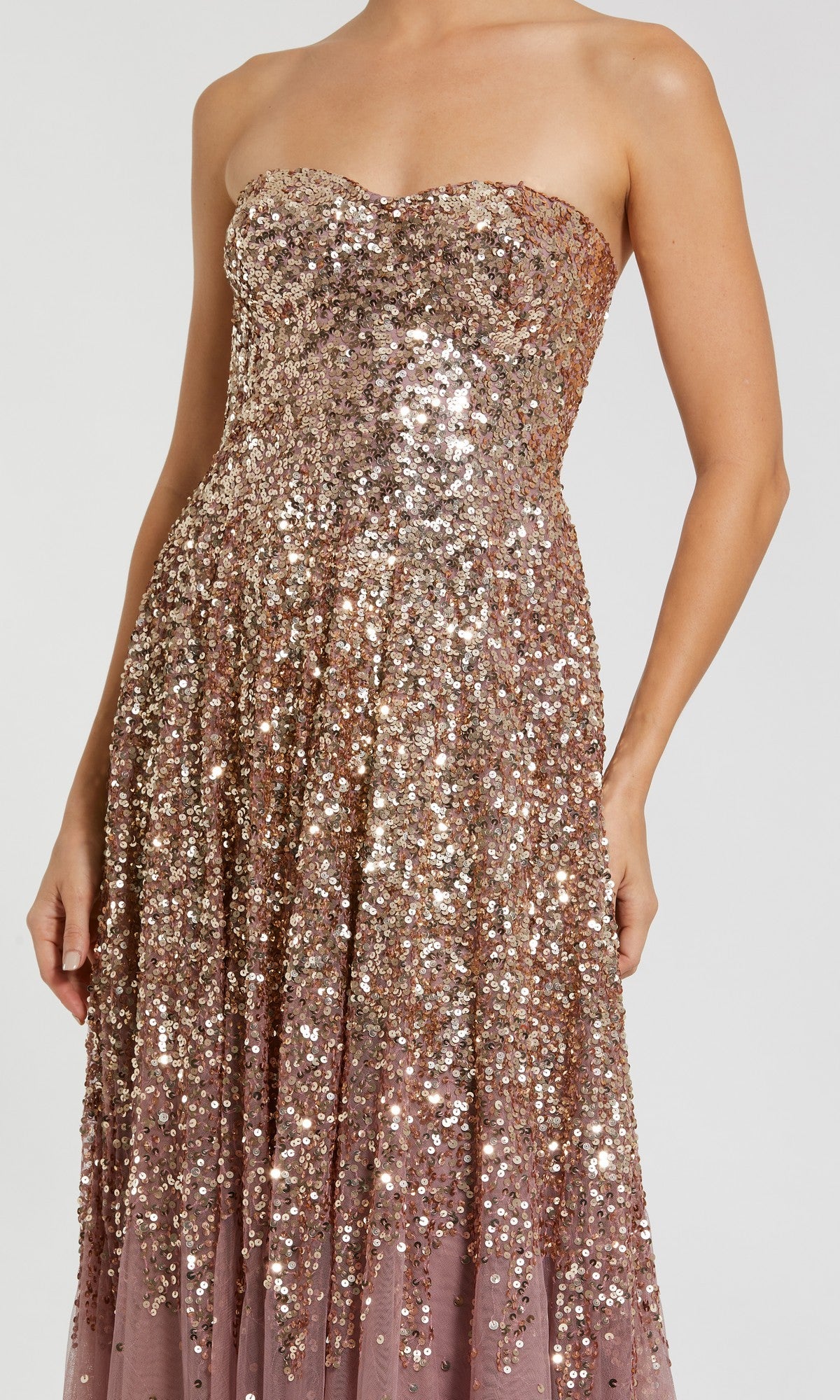 Wearing the Mac Duggal 6144 long formal dress, this person stuns in a strapless gown featuring a fitted bodice and flared skirt, adorned with shimmering gold and silver sequins that create a striking ombre effect from top to floor-length hem.